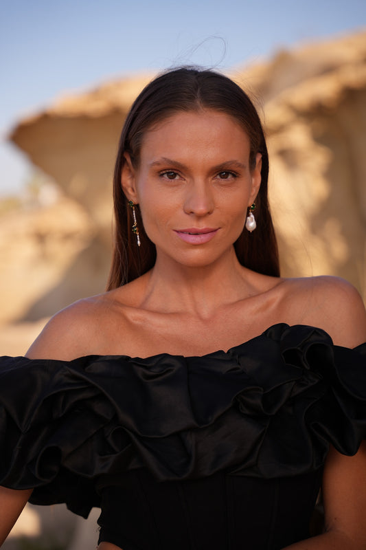 mujer con pendientes largos de perla y piedra verde